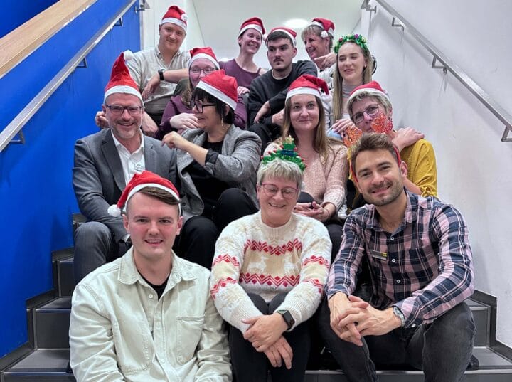 Gruppe von Menschen sitzen mit Weihnachtsmützen auf einer Treppe