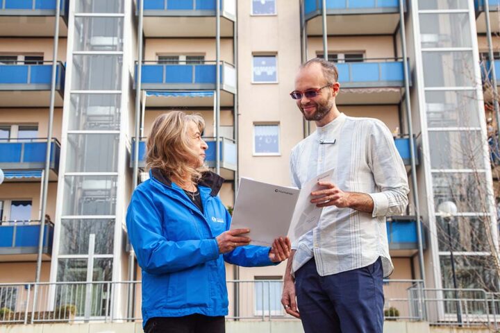 Ein Mann und eine Frau stehen vor einem großen Gebäude und überreichen sich einen Vertrag. ©Humanas Pflege GmbH & Co. KG